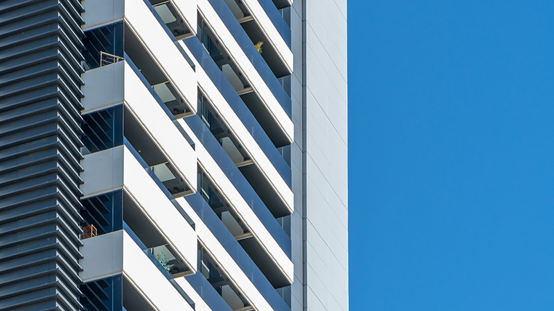Modern residential apartment building with clean lines and balconies, representing real assets and urban housing—relevant to Apollo’s capital solutions and alternative investments strategy.